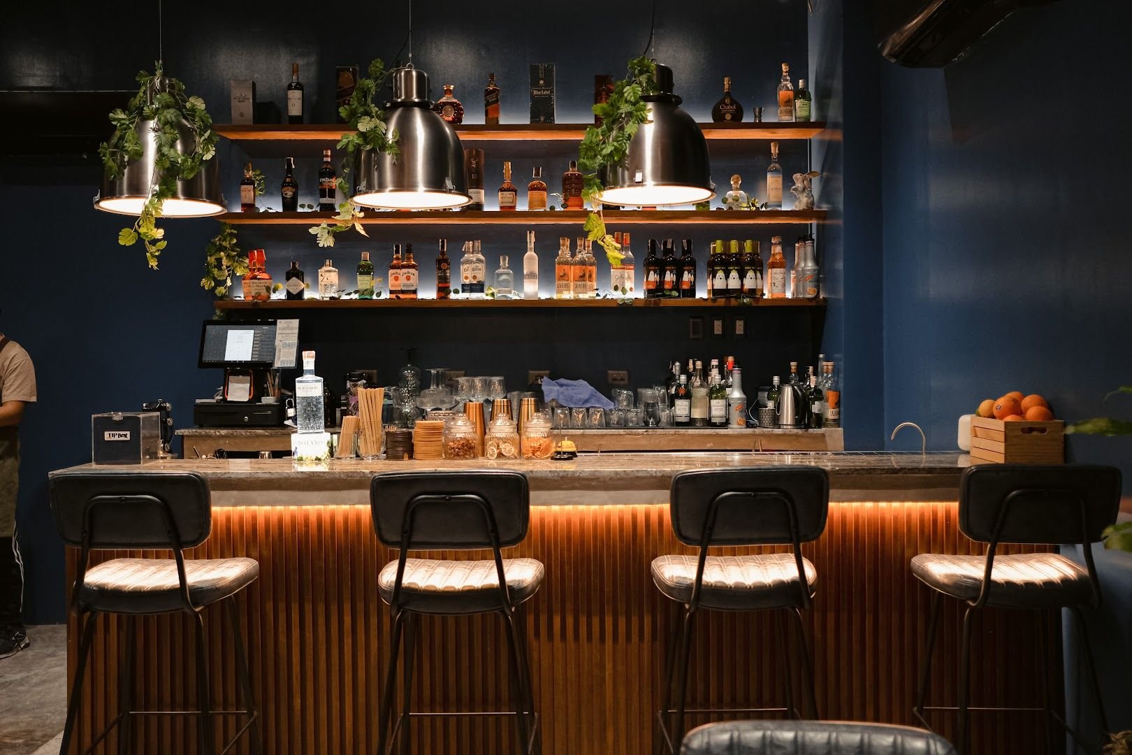 Rabbit Room bar area - cobalt blue walls with spirits on wooden shelves and leather bar stools